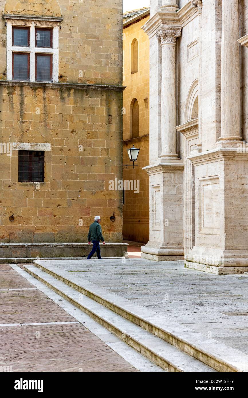 Un homme passe par la cathédrale de Pienza, une ville médiévale en Toscane, pleine de vieilles maisons et structures, également déclarée site du patrimoine de l'UNESCO. Banque D'Images
