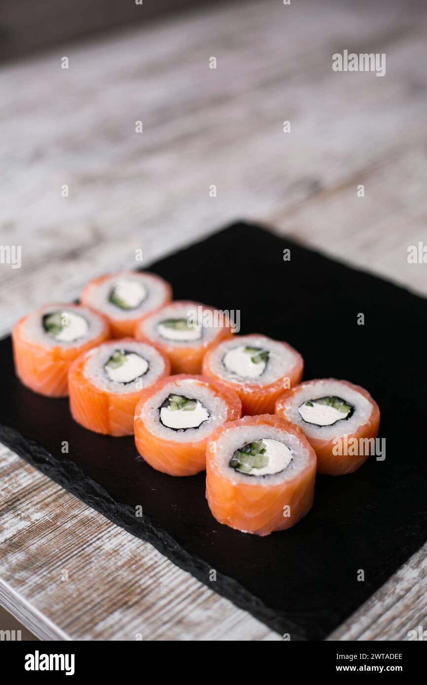sushi au saumon léger philadelphia sur un bureau noir, fond blanc, vue du dessus Banque D'Images