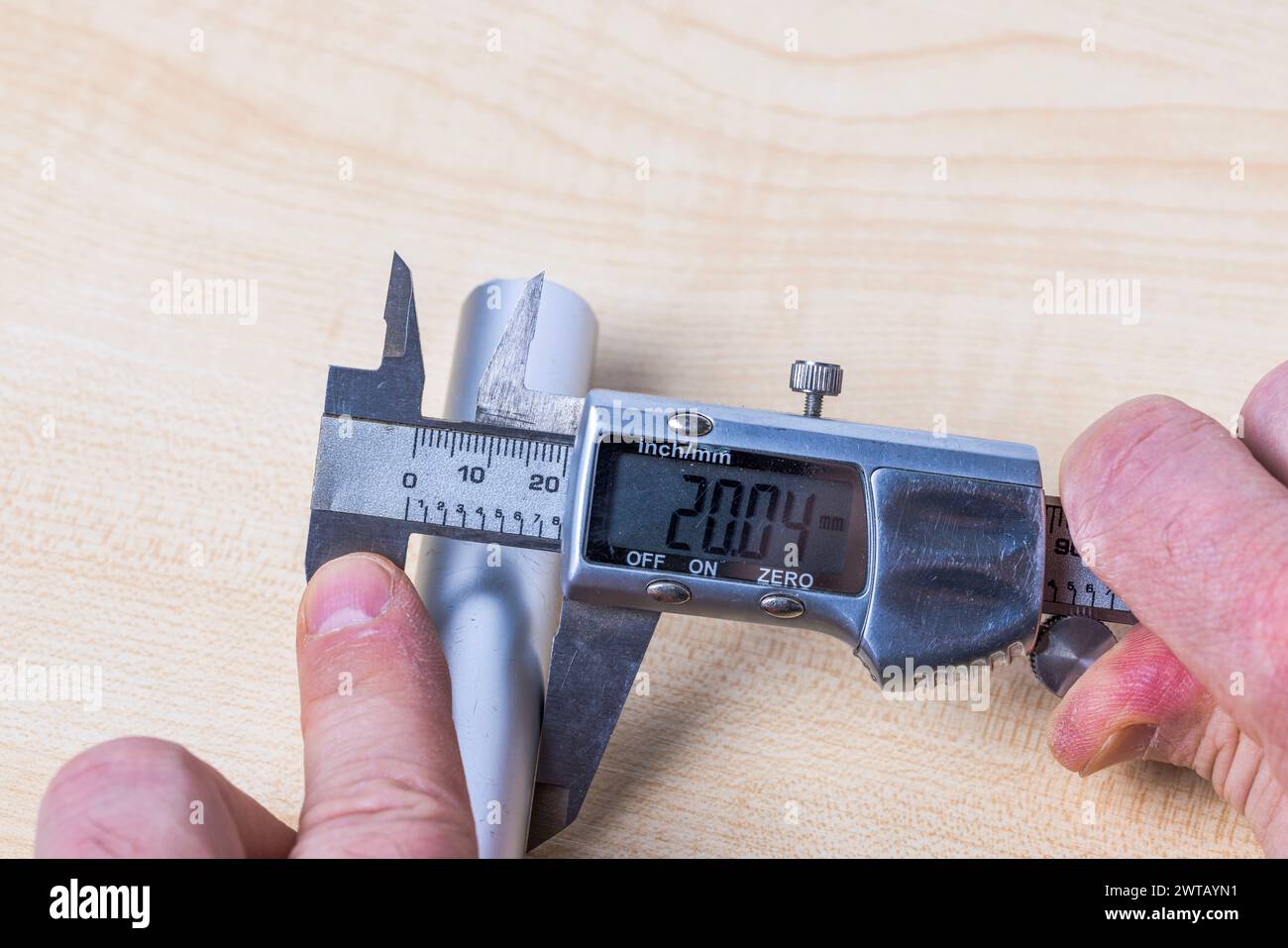 Vue rapprochée d'une personne mesurant le diamètre d'un tuyau en aluminium avec un pied à coulisse numérique. Banque D'Images