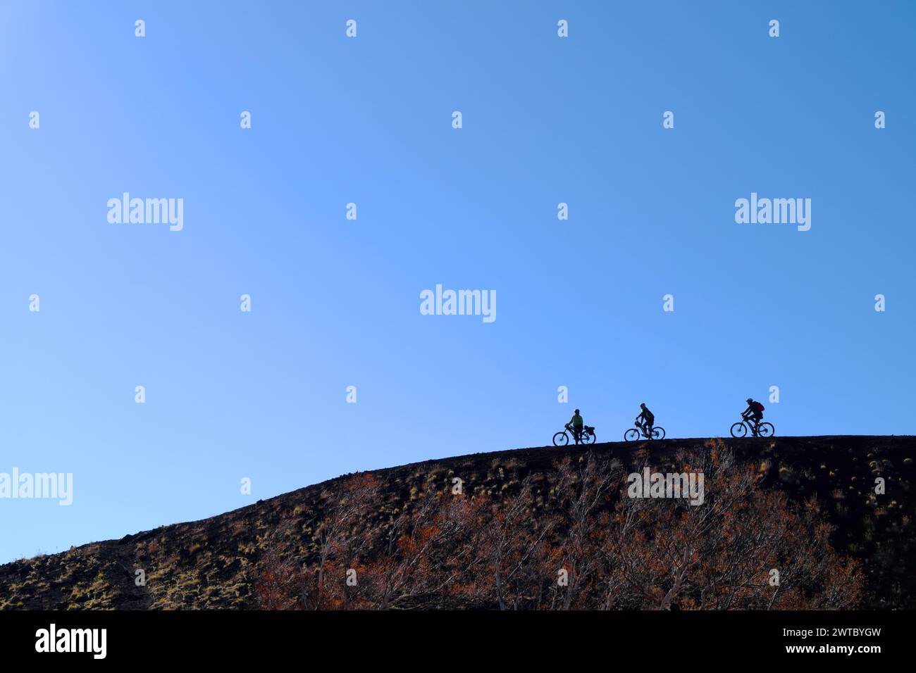 Silhouette de cyclistes sur le bord d'un cratère dans le parc de l'Etna, Sicile, Italie Banque D'Images