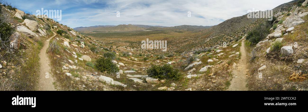 Une vue panoramique sur un désert avec un chemin de terre qui le traverse. La route est entourée de rochers et il n'y a pas d'arbres dans la région. Le ciel est nuageux Banque D'Images