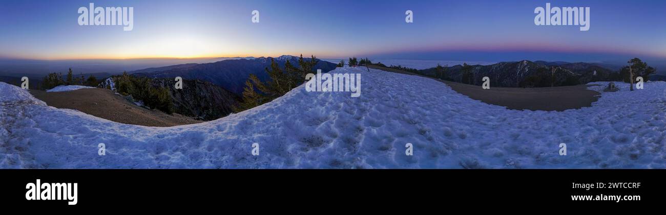 Une vue panoramique sur une montagne enneigée avec un beau coucher de soleil en arrière-plan. Le ciel est un mélange de teintes orange et violettes, créant un pois serein Banque D'Images