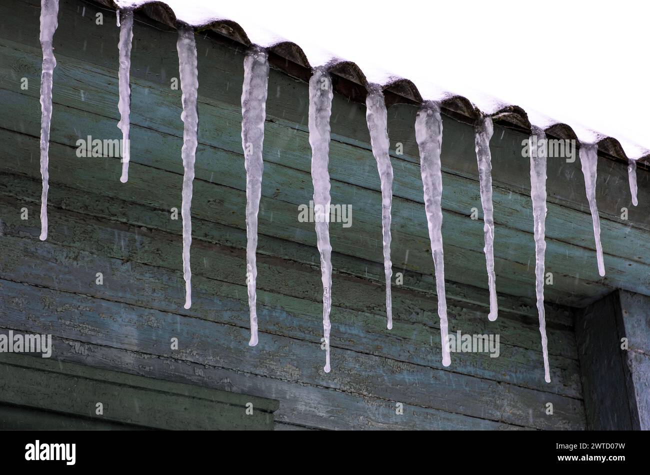 Glaces d'hiver suspendues aux avant--toits du toit. Banque D'Images