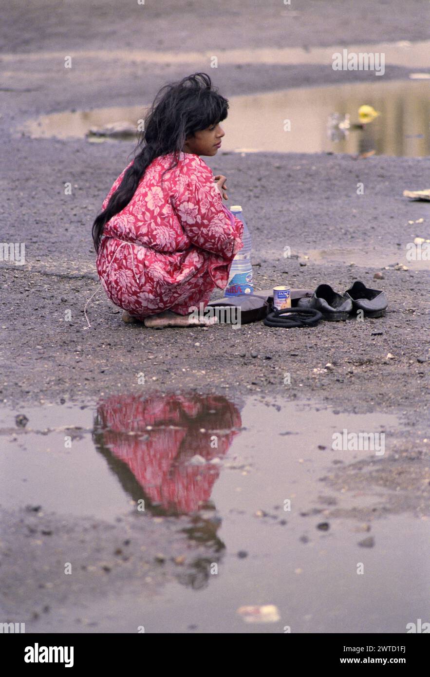 23 mars 1991 une fille irakienne squamée pieds nus parmi les flaques d'eau dans un camp de réfugiés près de Safwan dans le sud de l'Irak, près de la frontière avec le Koweït. Banque D'Images