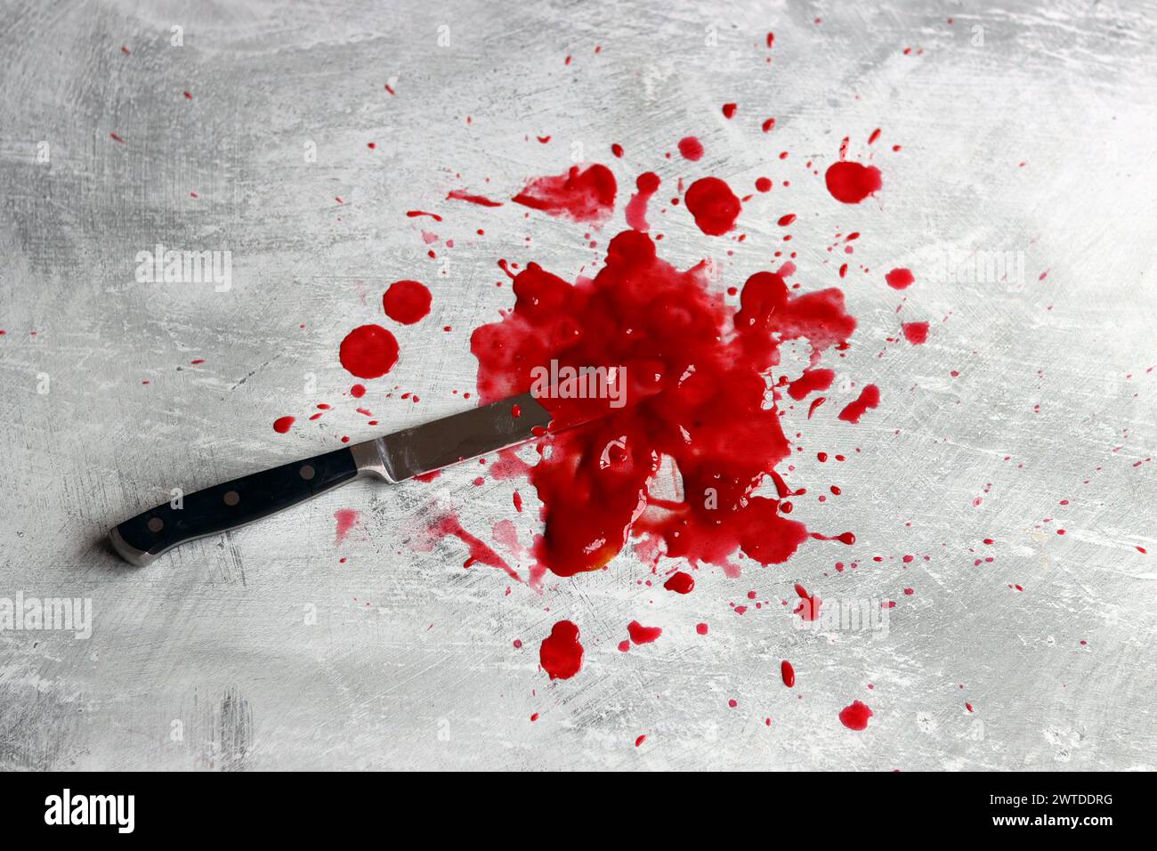 Couteau sanglant se trouve sur fond désordonné. Homicide concept de violence domestique. Piscine de sang. Fond texturé gris clair avec espace de copie. Banque D'Images