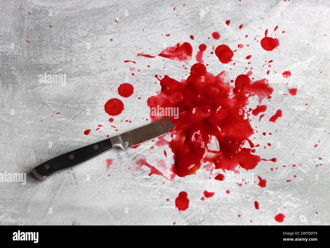 Couteau sanglant se trouve sur fond désordonné. Homicide concept de violence domestique. Piscine de sang. Fond texturé gris clair avec espace de copie. Banque D'Images