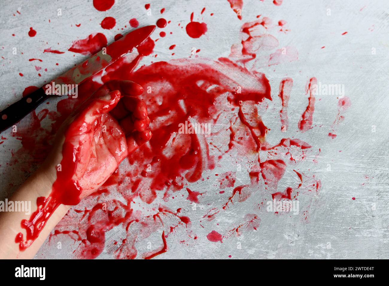 Couteau sanglant se trouve sur fond désordonné. Homicide concept de violence domestique. Piscine de sang. Fond texturé gris clair avec espace de copie. Banque D'Images