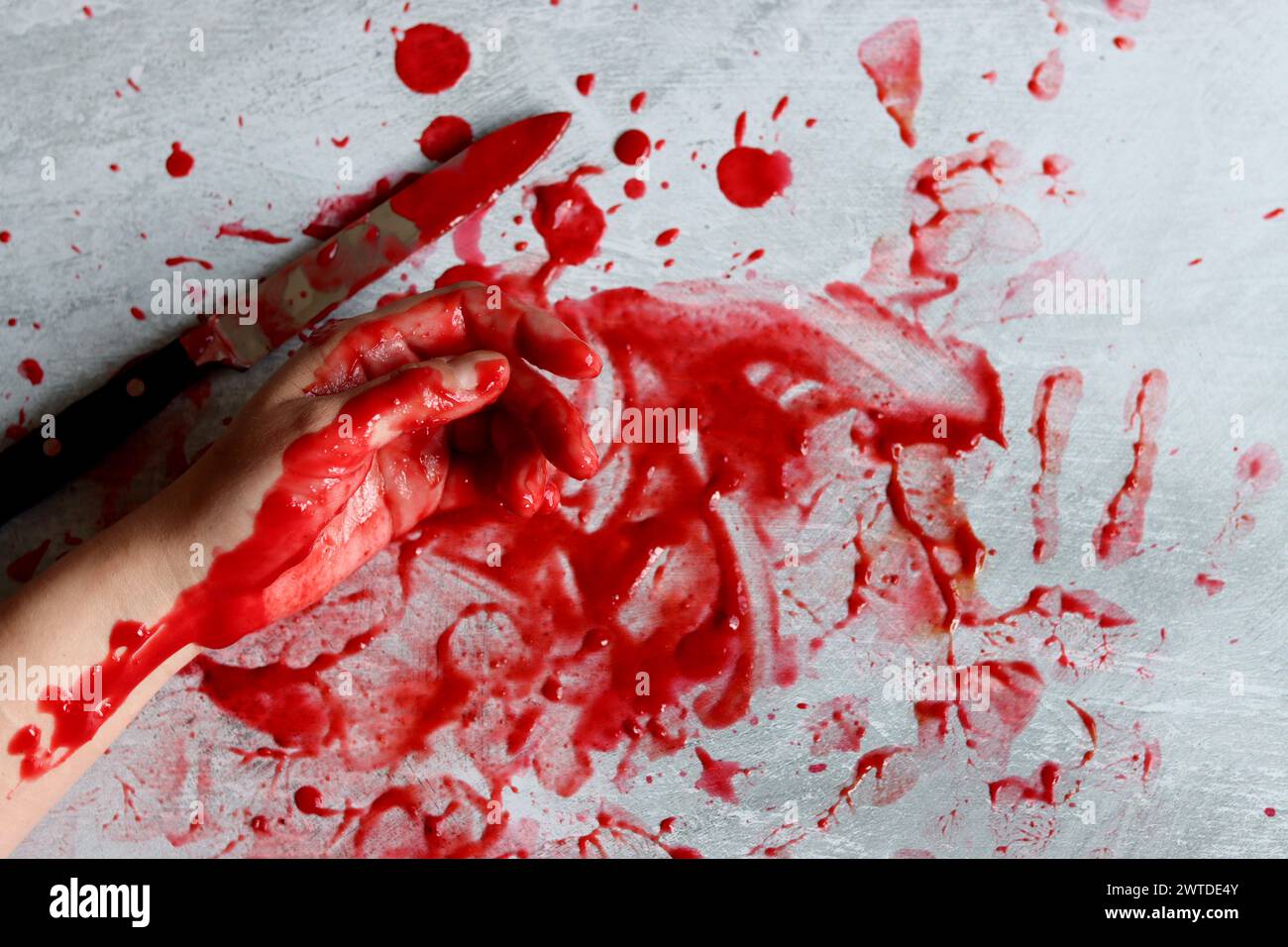 Couteau sanglant se trouve sur fond désordonné. Homicide concept de violence domestique. Piscine de sang. Fond texturé gris clair avec espace de copie. Banque D'Images