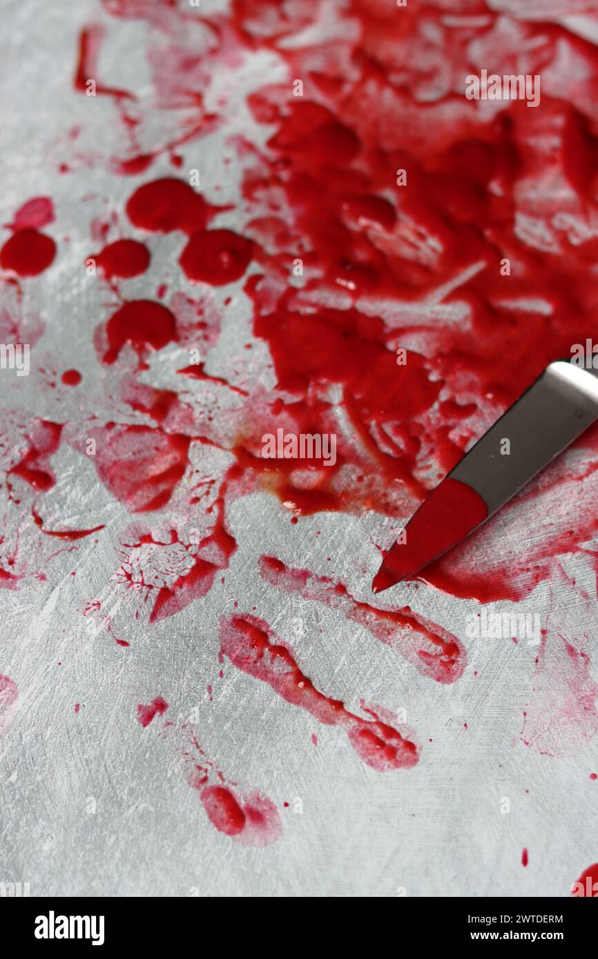 Couteau sanglant se trouve sur fond désordonné. Homicide concept de violence domestique. Piscine de sang. Fond texturé gris clair avec espace de copie. Banque D'Images