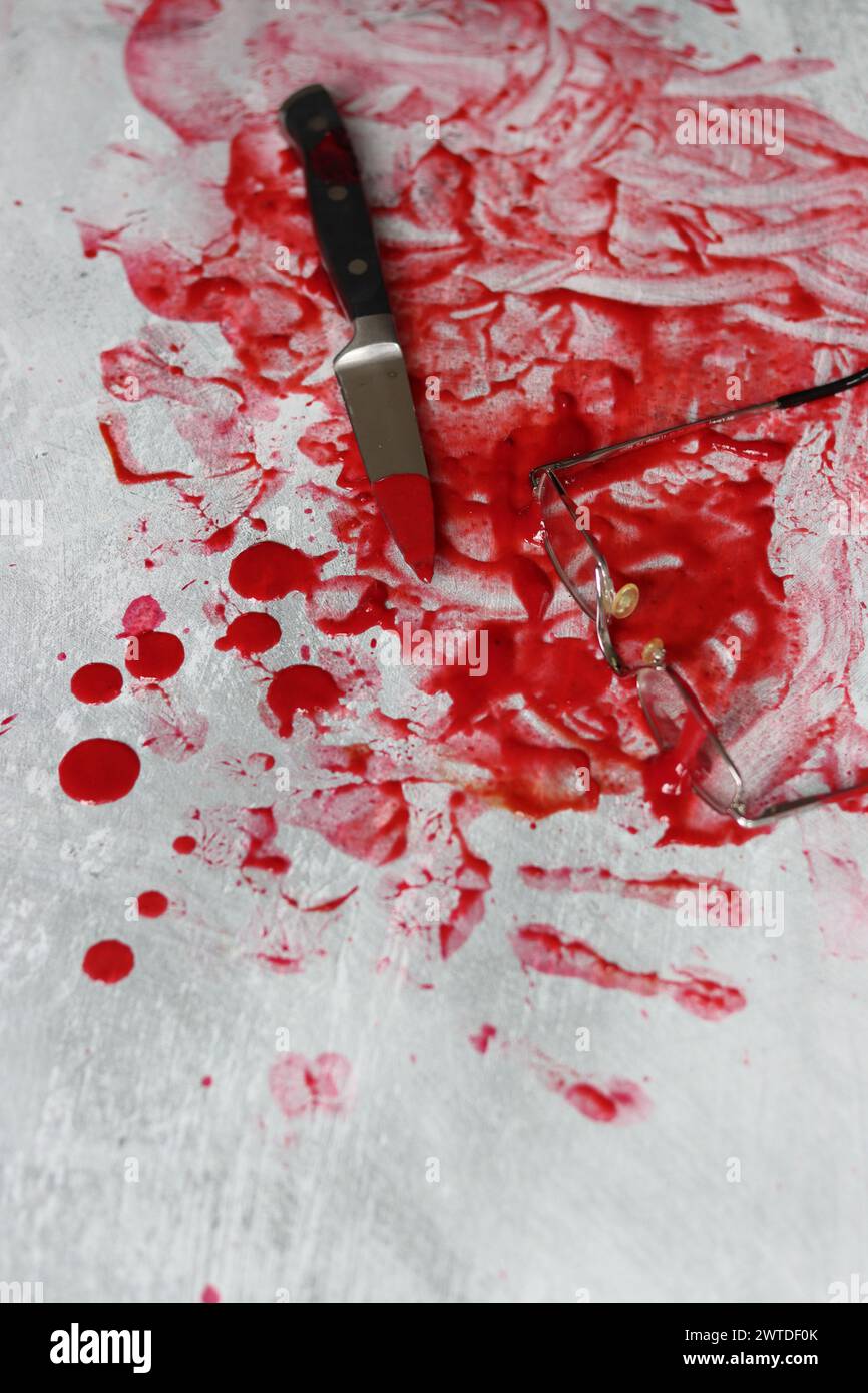 Couteau sanglant se trouve sur fond désordonné. Homicide concept de violence domestique. Piscine de sang. Fond texturé gris clair avec espace de copie. Banque D'Images