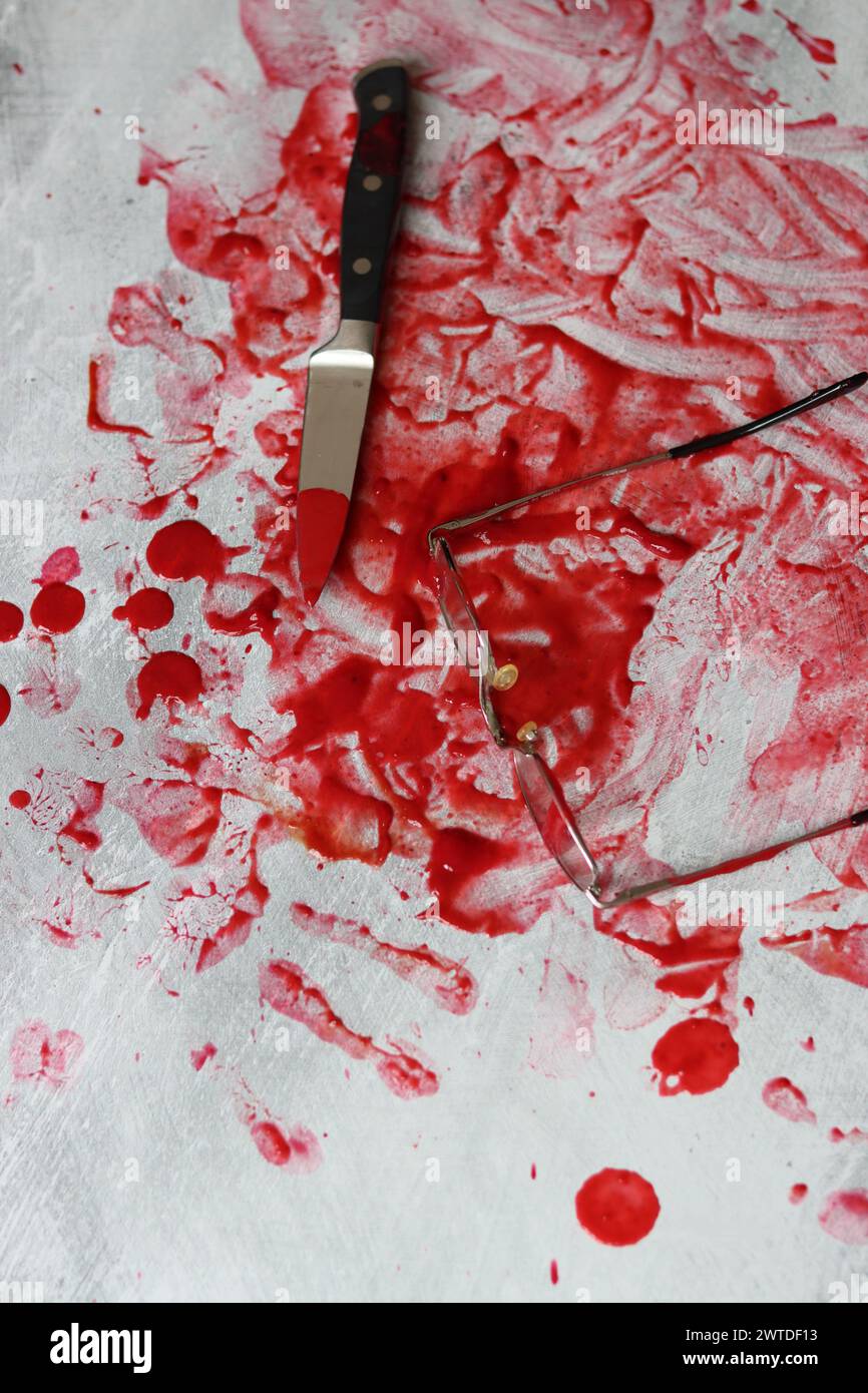 Couteau sanglant se trouve sur fond désordonné. Homicide concept de violence domestique. Piscine de sang. Fond texturé gris clair avec espace de copie. Banque D'Images