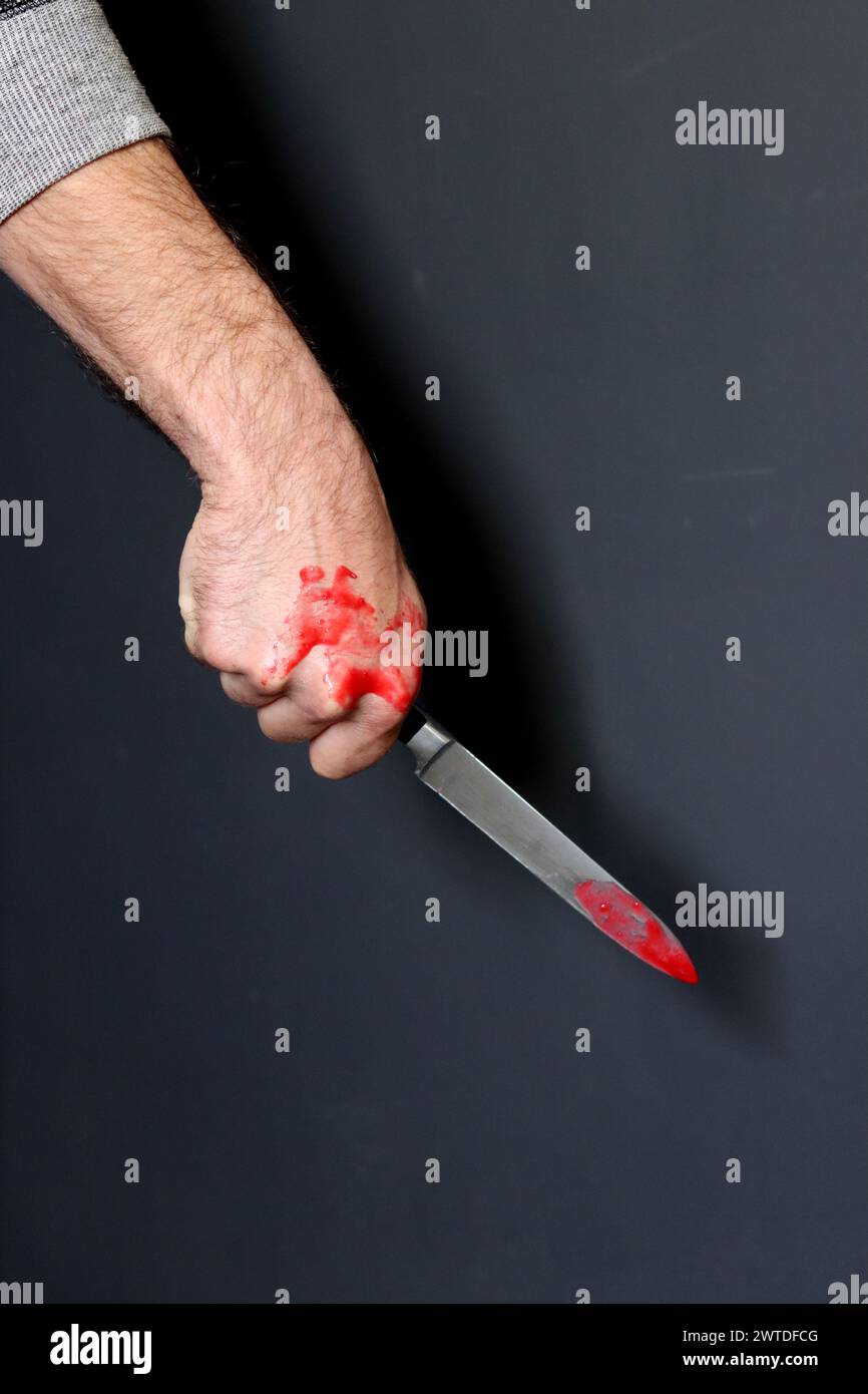 Main sanglante tenant un couteau avec du sang sur un fond noir. Violence domestique Abuse concept de meurtre Banque D'Images