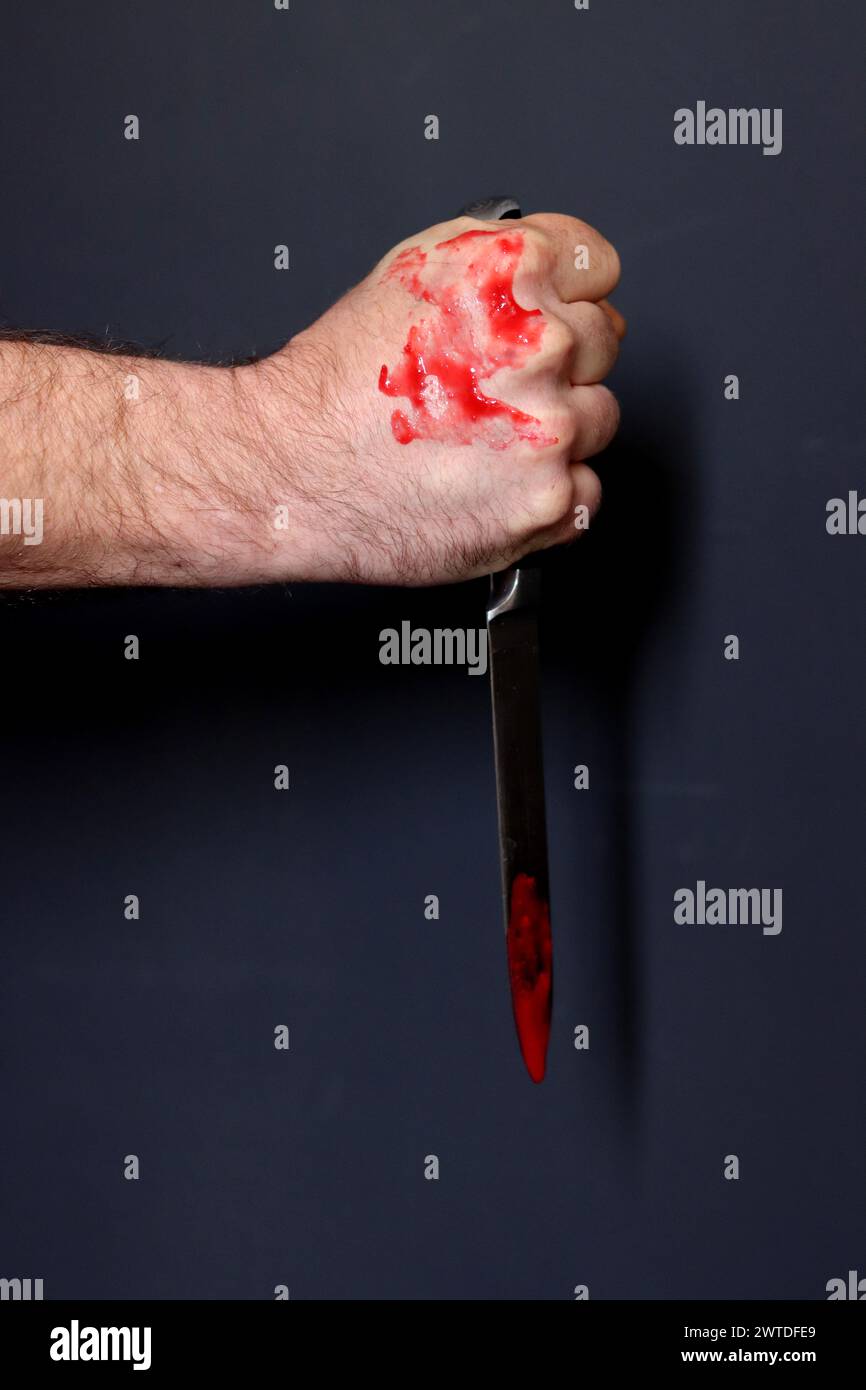 Main sanglante tenant un couteau avec du sang sur un fond noir. Violence domestique Abuse concept de meurtre Banque D'Images