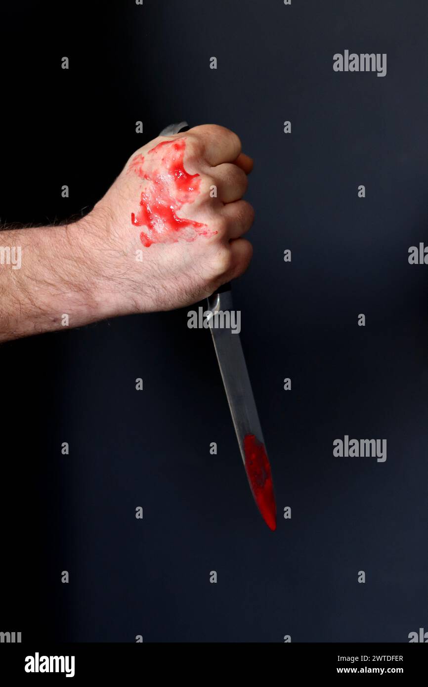 Main sanglante tenant un couteau avec du sang sur un fond noir. Violence domestique Abuse concept de meurtre Banque D'Images