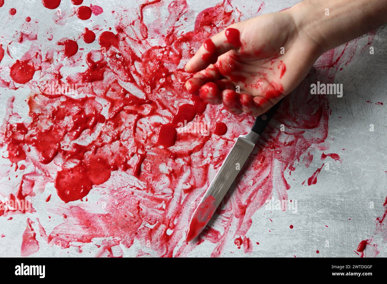 Couteau sanglant se trouve sur fond désordonné. Homicide concept de violence domestique. Piscine de sang. Fond texturé gris clair avec espace de copie. Banque D'Images