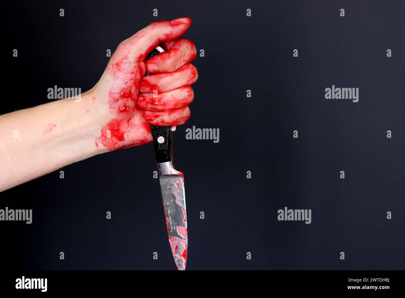 Main sanglante tenant un couteau avec du sang sur un fond noir. Violence domestique Abuse concept de meurtre Banque D'Images