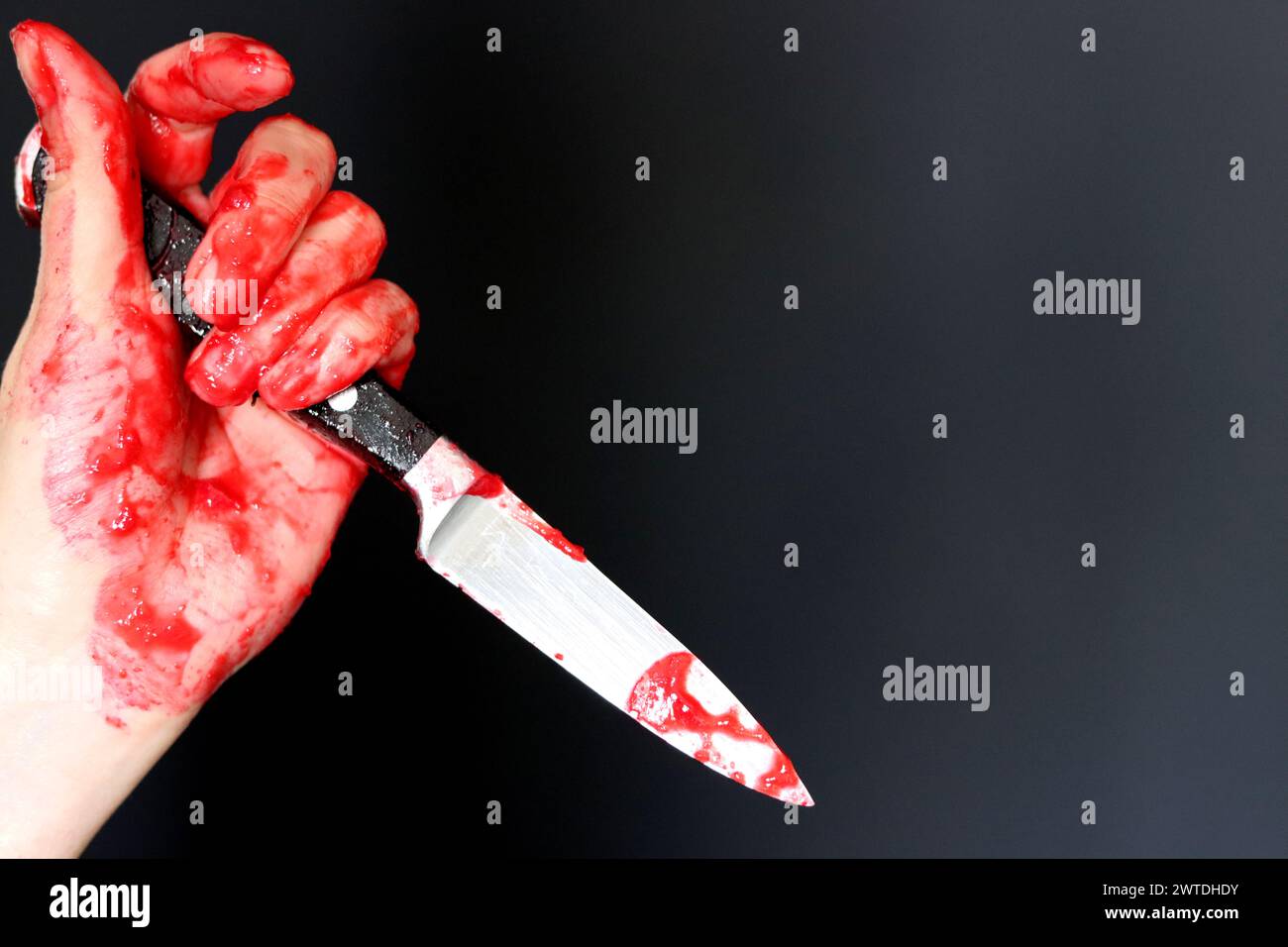 Main sanglante tenant un couteau avec du sang sur un fond noir. Violence domestique Abuse concept de meurtre Banque D'Images