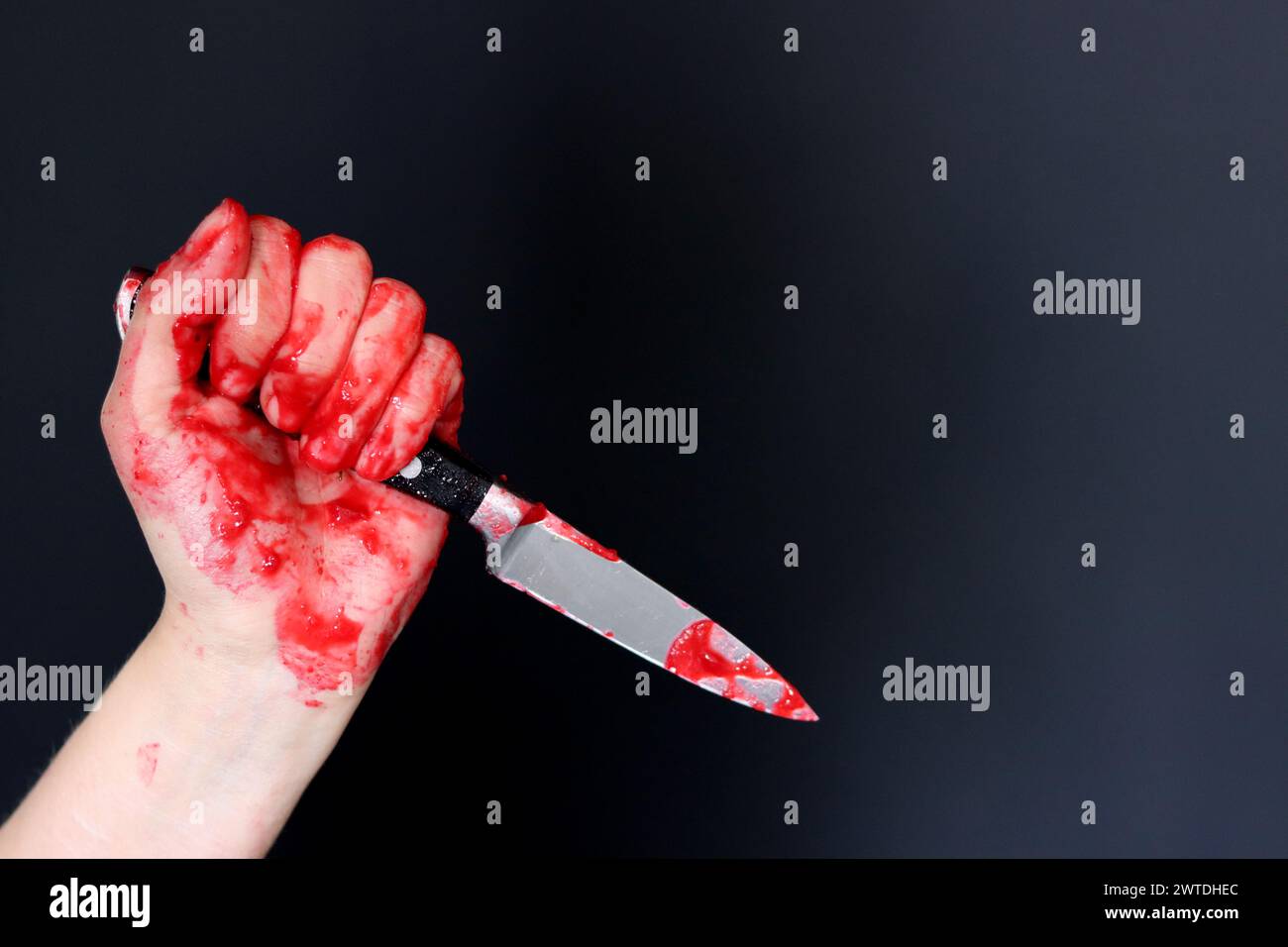 Main sanglante tenant un couteau avec du sang sur un fond noir. Violence domestique Abuse concept de meurtre Banque D'Images
