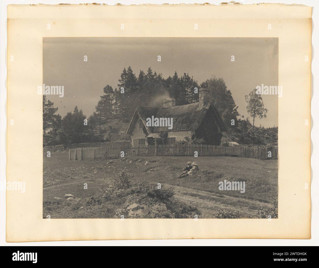 Robert et Emily Curwen, North Loch an-Eilein. Probablement Robert Ewing Curwen, photographe (britannique, vers 1841 - 1934) de 1880 à 1885 deux enfants, Robert et Emily Curwen, couchés dans l'herbe devant un chalet. Le chalet a un toit de chaume et deux cheminées. Une clôture en bois entoure le chalet. (Verso, monture) en bas à droite, crayon : '12'; Banque D'Images