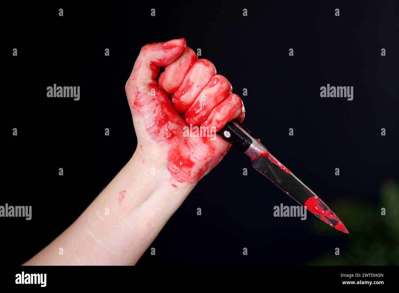 Main sanglante tenant un couteau avec du sang sur un fond noir. Violence domestique Abuse concept de meurtre Banque D'Images