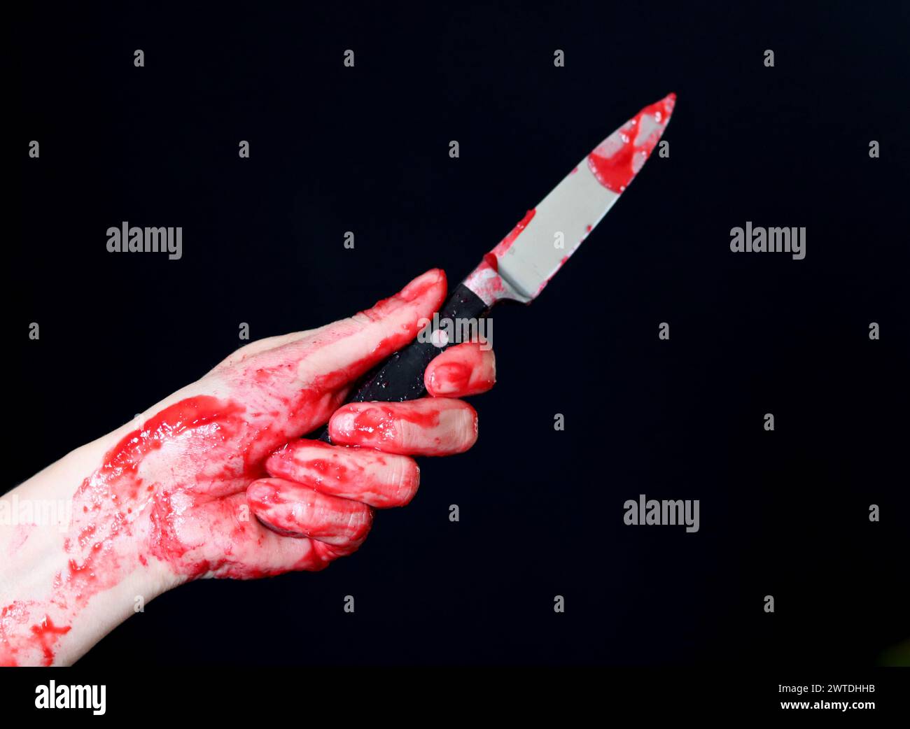 Main sanglante tenant un couteau avec du sang sur un fond noir. Violence domestique Abuse concept de meurtre Banque D'Images