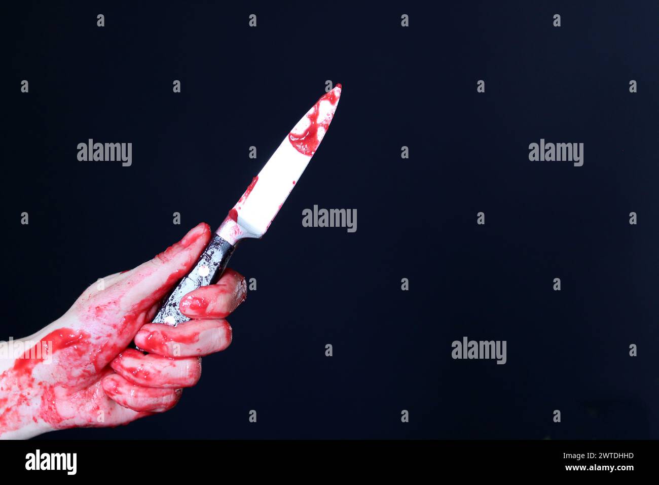Main sanglante tenant un couteau avec du sang sur un fond noir. Violence domestique Abuse concept de meurtre Banque D'Images