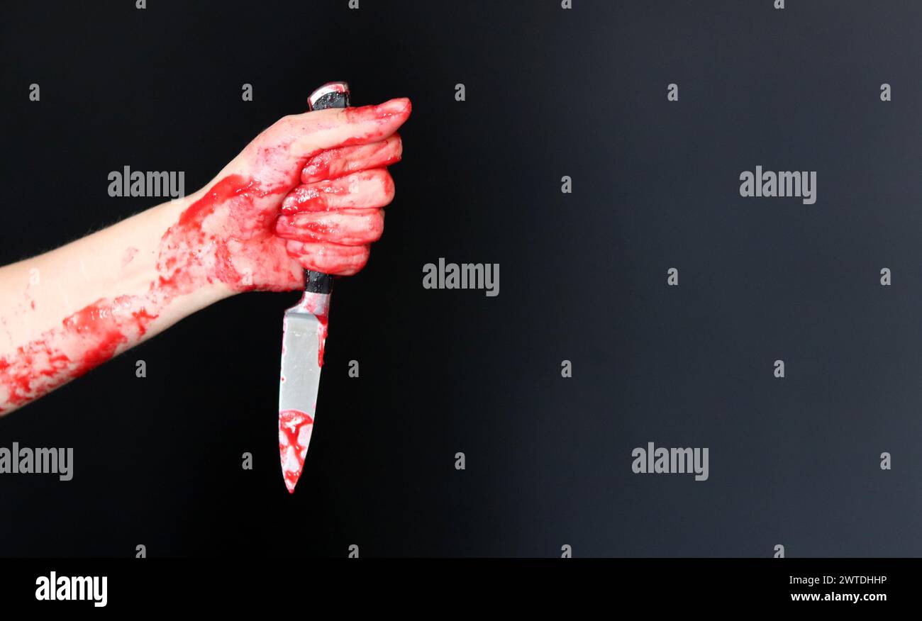 Main sanglante tenant un couteau avec du sang sur un fond noir. Violence domestique Abuse concept de meurtre Banque D'Images