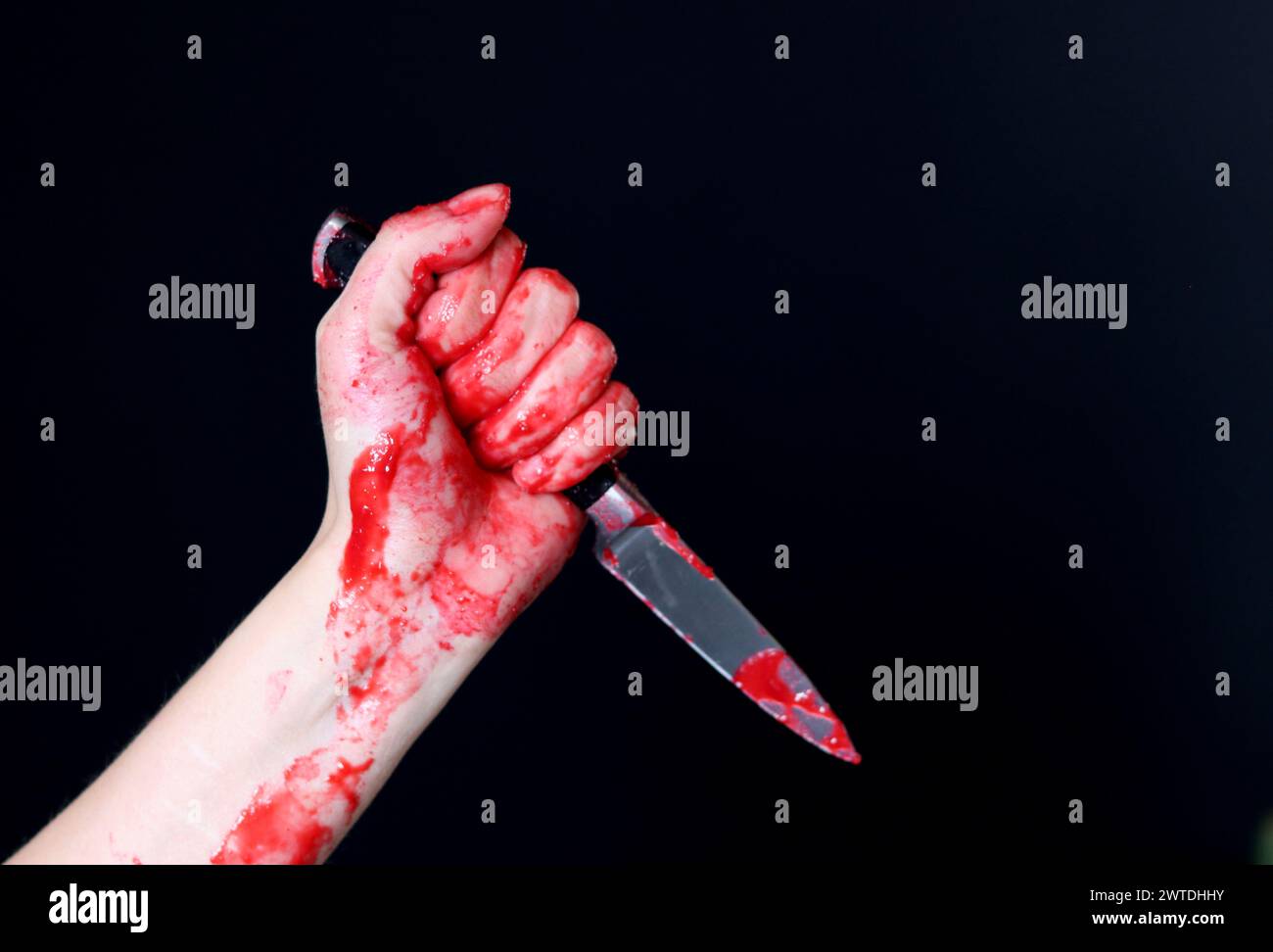 Main sanglante tenant un couteau avec du sang sur un fond noir. Violence domestique Abuse concept de meurtre Banque D'Images