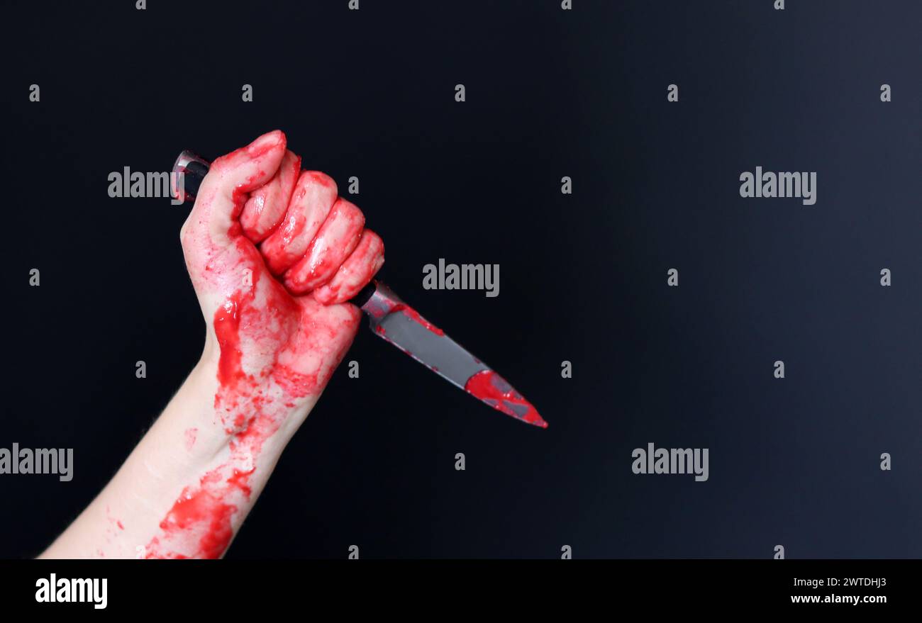 Main sanglante tenant un couteau avec du sang sur un fond noir. Violence domestique Abuse concept de meurtre Banque D'Images