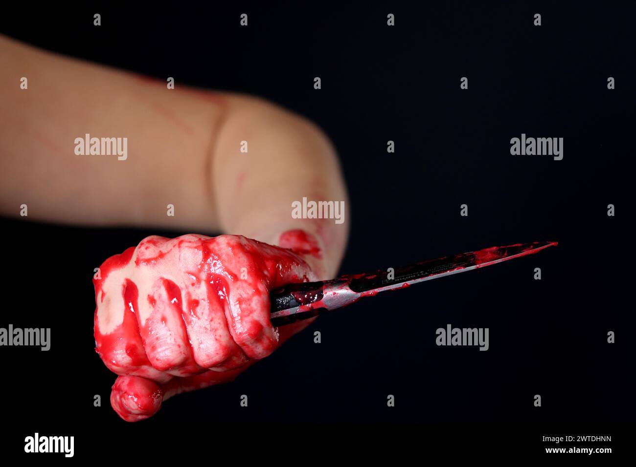 Main sanglante tenant un couteau avec du sang sur un fond noir. Violence domestique Abuse concept de meurtre Banque D'Images