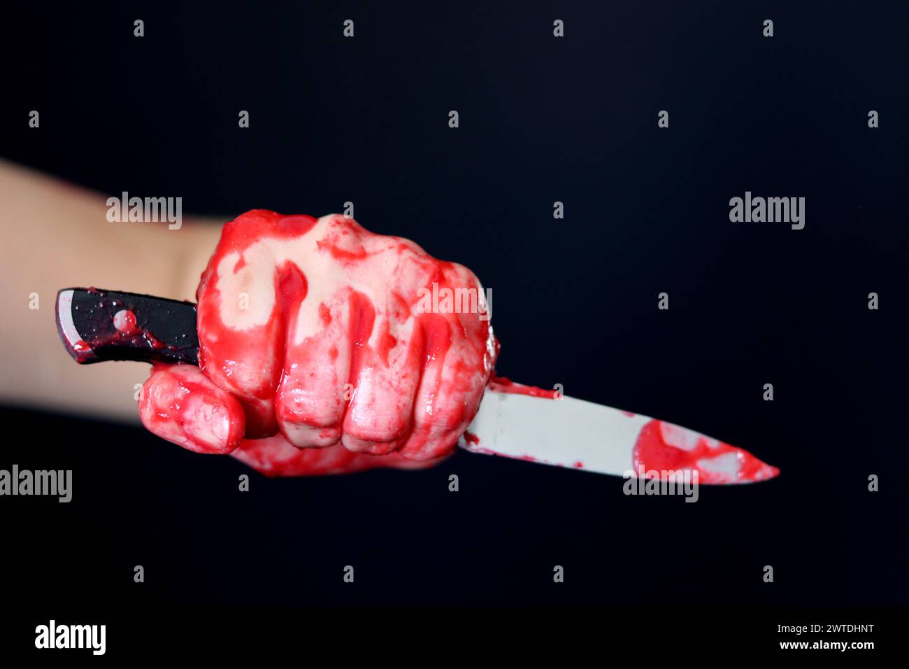 Main sanglante tenant un couteau avec du sang sur un fond noir. Violence domestique Abuse concept de meurtre Banque D'Images