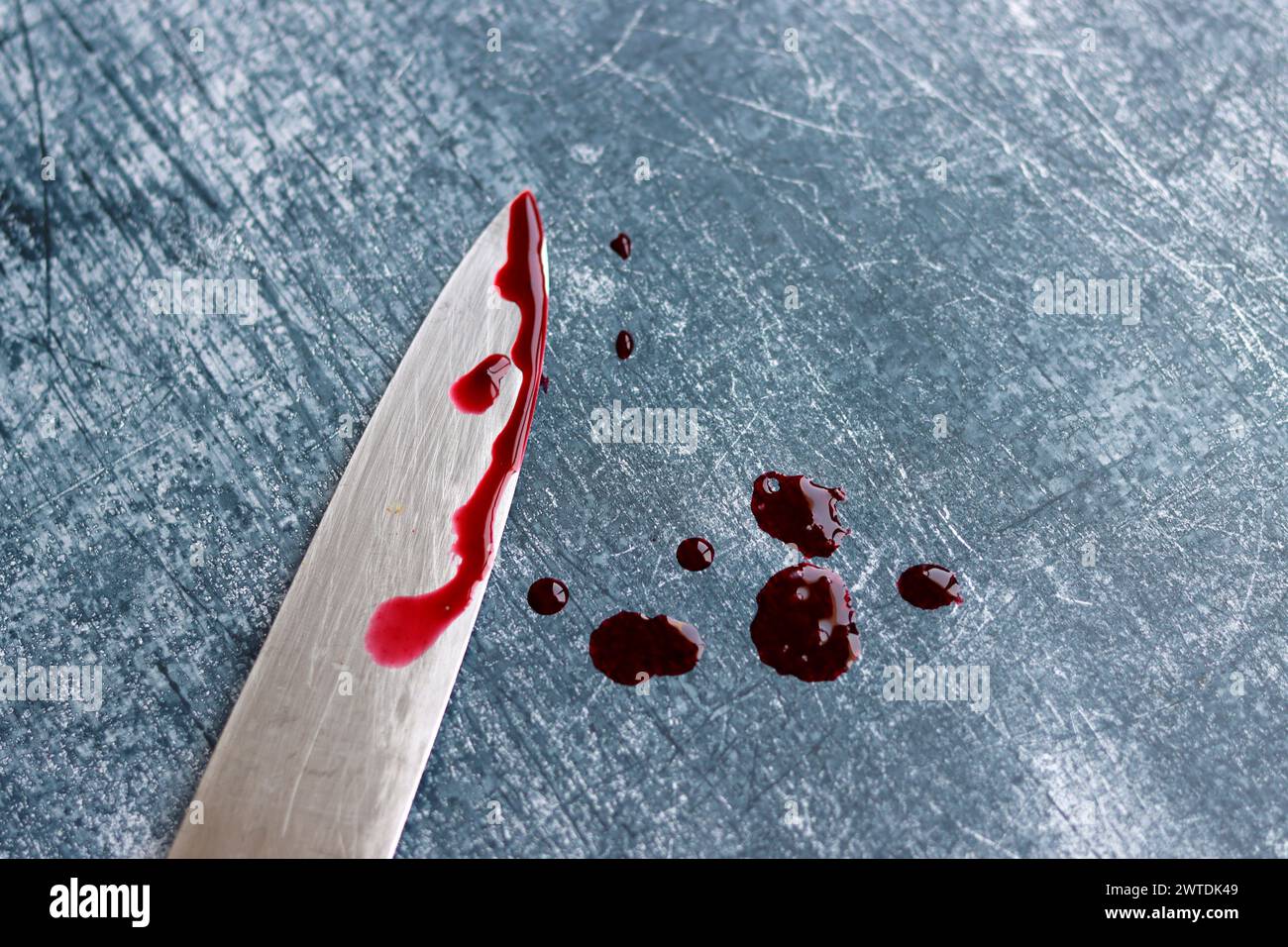 Gros couteau sanglant sur fond gris grungy avec espace de copie. Gouttes de sang sur fond rouillé. Concept de violence domestique. Banque D'Images