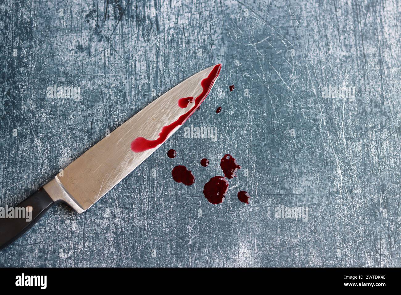 Gros couteau sanglant sur fond gris grungy avec espace de copie. Gouttes de sang sur fond rouillé. Concept de violence domestique. Banque D'Images