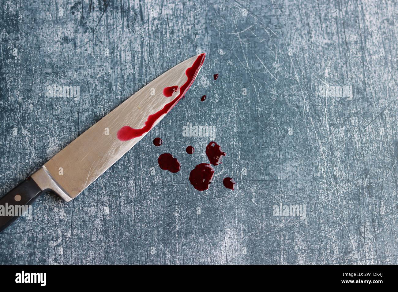 Gros couteau sanglant sur fond gris grungy avec espace de copie. Gouttes de sang sur fond rouillé. Concept de violence domestique. Banque D'Images