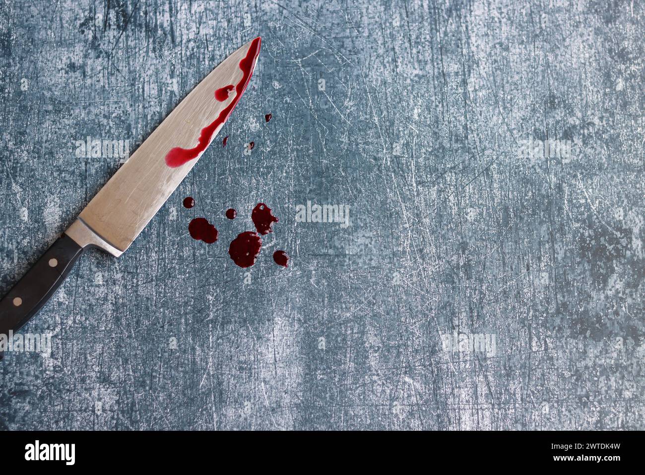 Gros couteau sanglant sur fond gris grungy avec espace de copie. Gouttes de sang sur fond rouillé. Concept de violence domestique. Banque D'Images