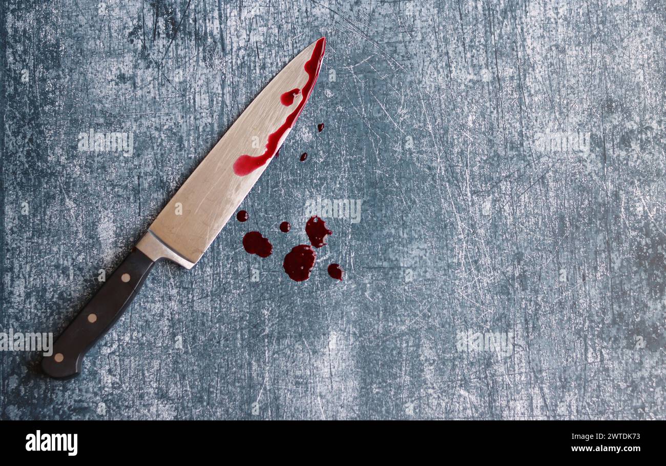 Gros couteau sanglant sur fond gris grungy avec espace de copie. Gouttes de sang sur fond rouillé. Concept de violence domestique. Banque D'Images