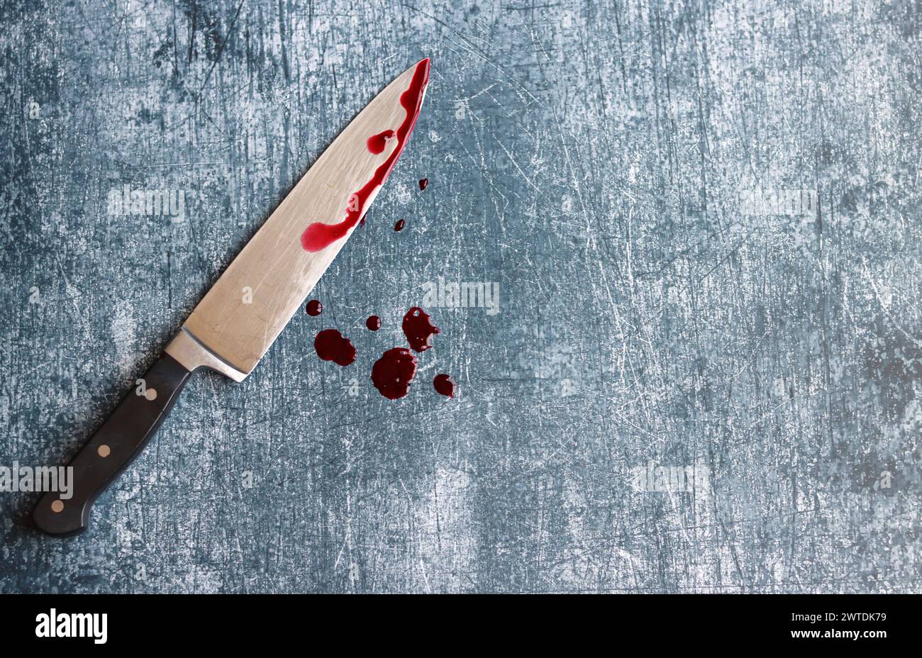 Gros couteau sanglant sur fond gris grungy avec espace de copie. Gouttes de sang sur fond rouillé. Concept de violence domestique. Banque D'Images