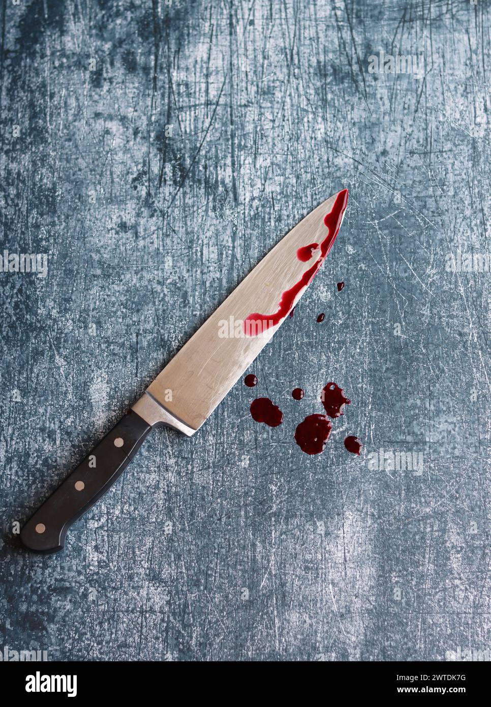 Gros couteau sanglant sur fond gris grungy avec espace de copie. Gouttes de sang sur fond rouillé. Concept de violence domestique. Banque D'Images