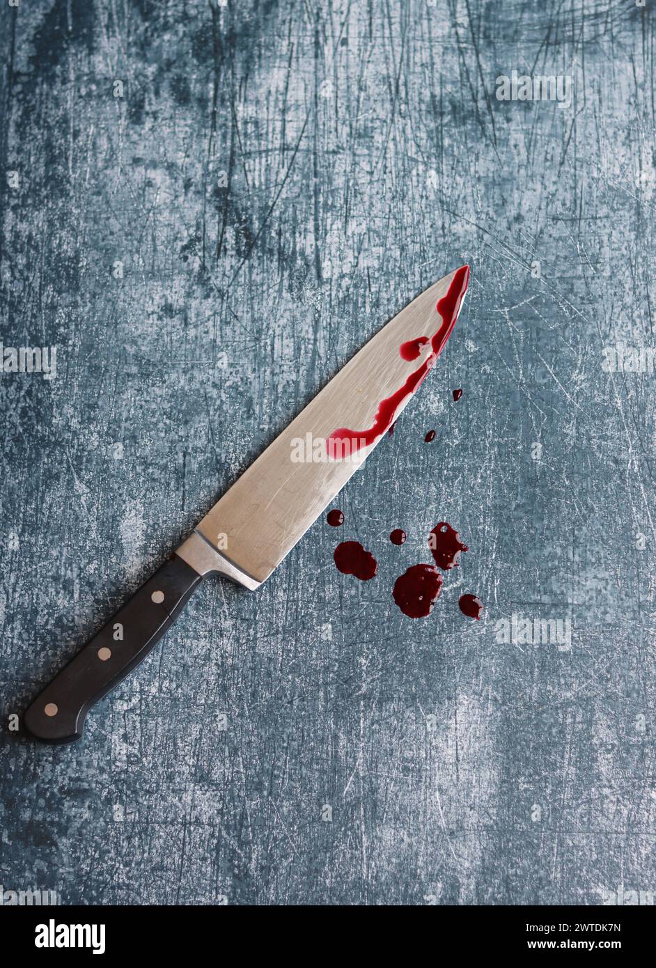 Gros couteau sanglant sur fond gris grungy avec espace de copie. Gouttes de sang sur fond rouillé. Concept de violence domestique. Banque D'Images