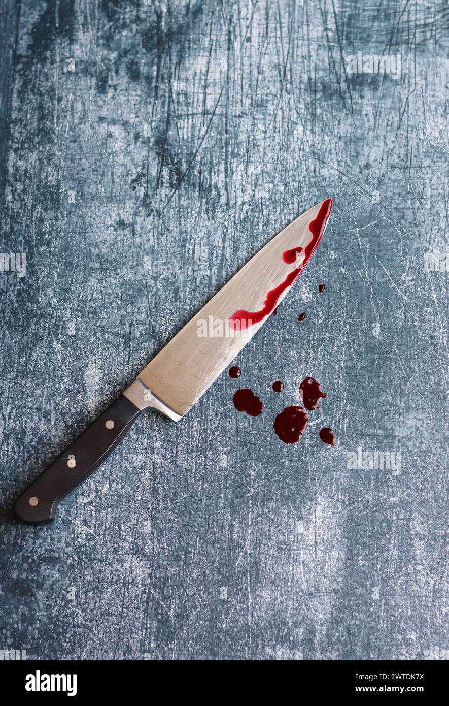 Gros couteau sanglant sur fond gris grungy avec espace de copie. Gouttes de sang sur fond rouillé. Concept de violence domestique. Banque D'Images