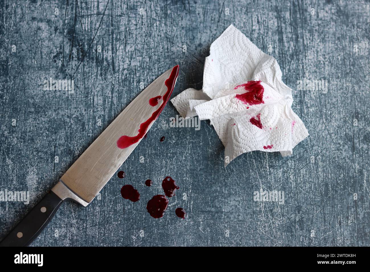 Gros couteau sanglant sur fond gris grungy avec espace de copie. Gouttes de sang sur fond rouillé. Concept de violence domestique. Banque D'Images