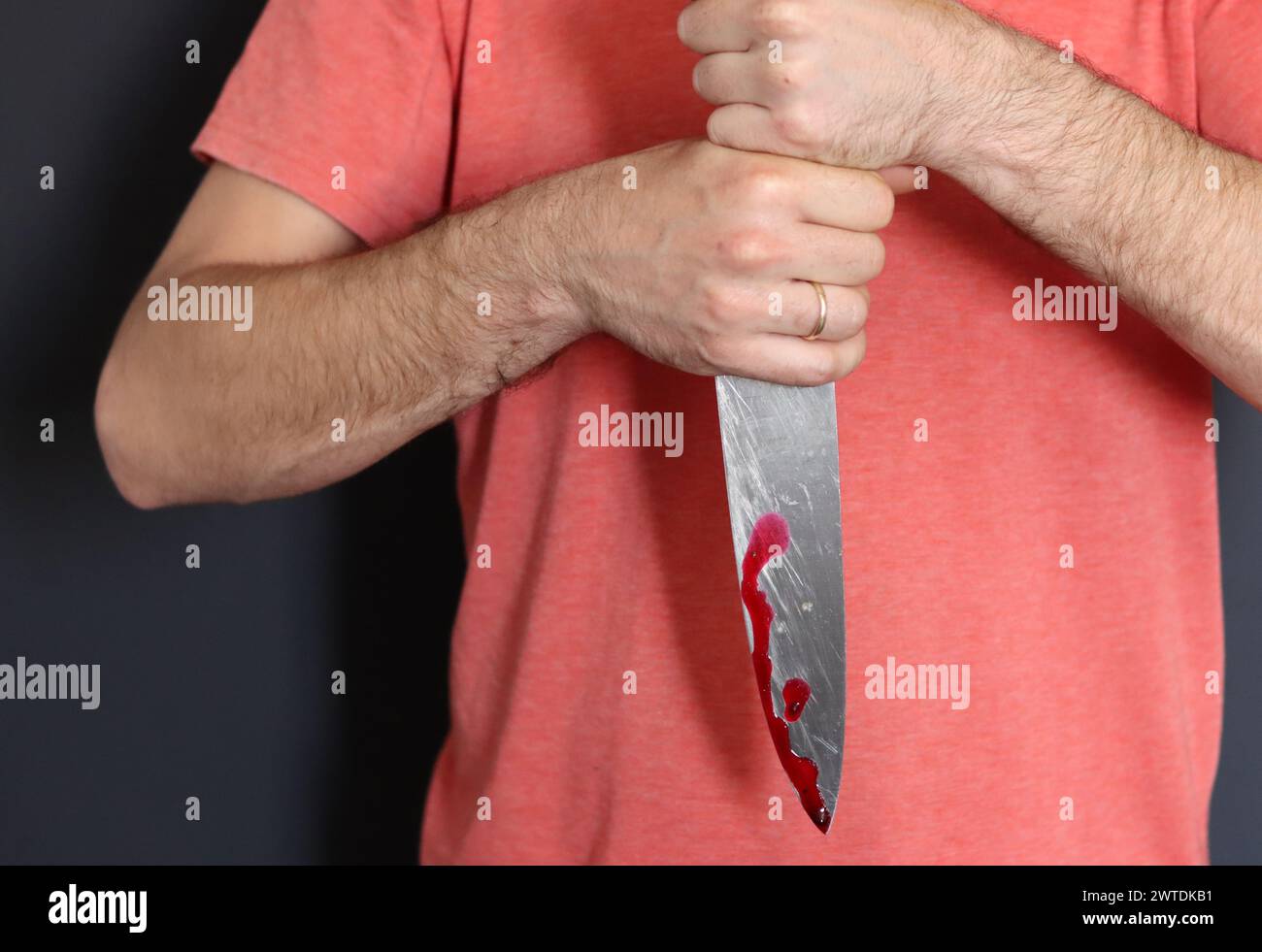 Homme tenant couteau avec du sang sur fond sombre, gros plan. Concept de violence domestique Banque D'Images