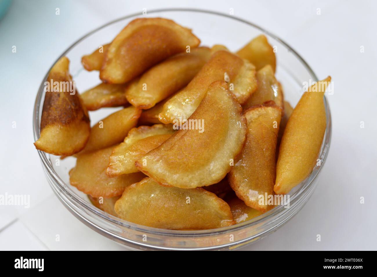 Un bol de boulettes de qatayef farcies et remplies de noix et de noix de coco râpées frits dans l'huile profonde et imbibées de sirop de sucre, dessert arabe plat plié Banque D'Images