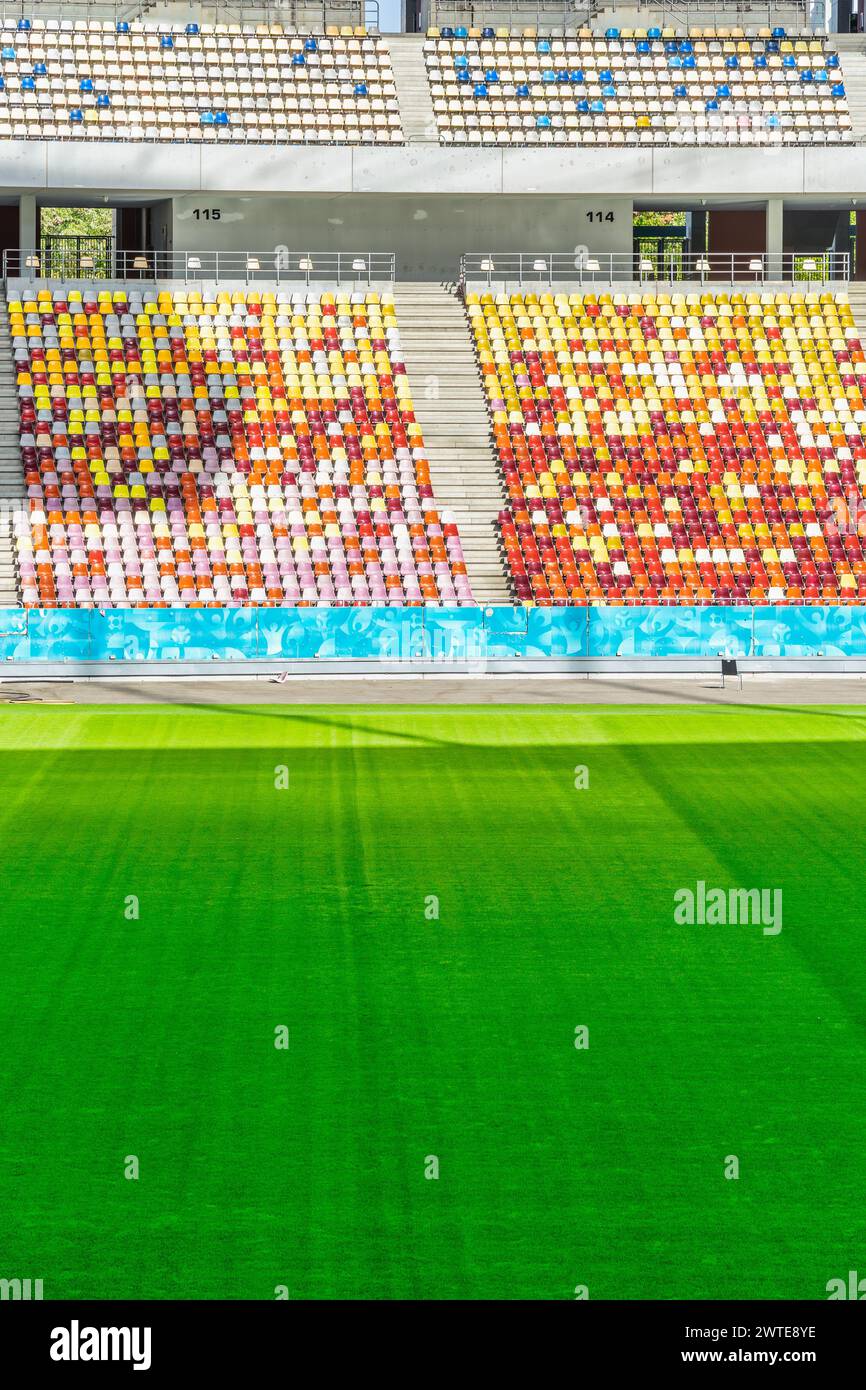 Stade vide avec des chaises colorées en tribune et l'herbe verte de pelouse Banque D'Images