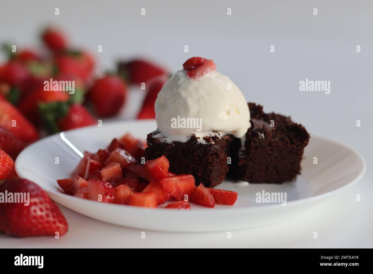 Brownie au chocolat avec fraises fraîches et une boule de crème glacée crémeuse à la vanille, parfait pour les menus de desserts et les envies sucrées. Avec Egg Less pr Banque D'Images