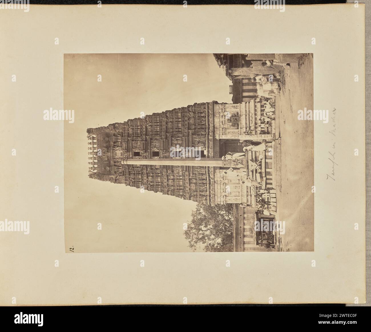 Temple à Madras. Inconnu, photographe vers 1866–1870 vue du gopuram, ou porte du temple au toit en tonneau, du temple Sri Someshwara Swamy. Devant elle se trouve une haute colonne, posée sur un piédestal sculpté. Un certain nombre de personnes peuvent être vues par le gopuram et la colonne. (Recto, impression) en haut à gauche, à l'encre noire : '12.' ; (verso, impression) en bas à droite, sur support non identifié, visible à travers la monture au verso : 'The Ulsoor Temple / Bangalore' ; (recto, montage) en bas au centre, au crayon : 'Temple in Madras [inscription inexacte]' ; (verso, montage) en bas à droite, au crayon : 'A48.49 [latéralement]'; Banque D'Images