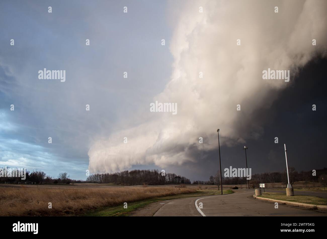 Un immense nuage de plateau et un orage violent approchent rapidement avec une route et des lampadaires au premier plan Banque D'Images