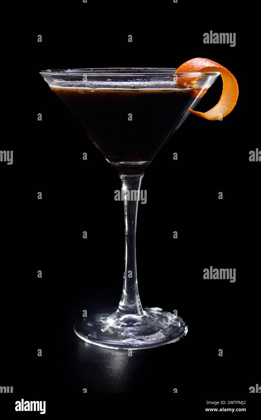 Un verre à martini avec une tranche de zeste d'orange sur le dessus. Le verre est rempli d'un liquide sombre Banque D'Images