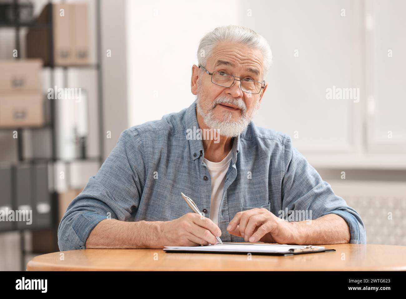 Homme senior signant dernier testament et testament à table à l'intérieur Banque D'Images