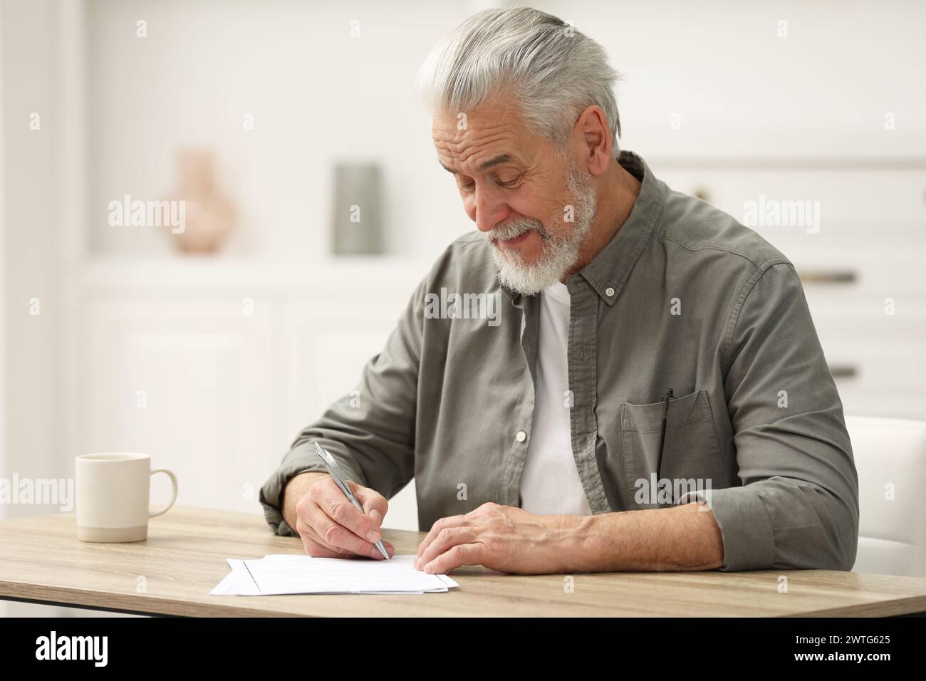 Homme senior signant dernier testament et testament à table à l'intérieur. Espace pour le texte Banque D'Images